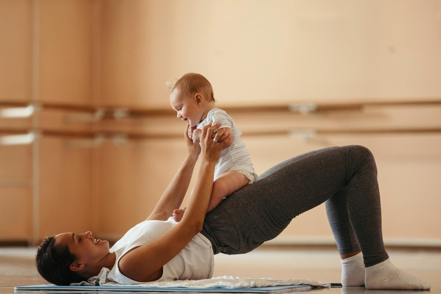 A mother doing a gentle core exercise on a mat at home